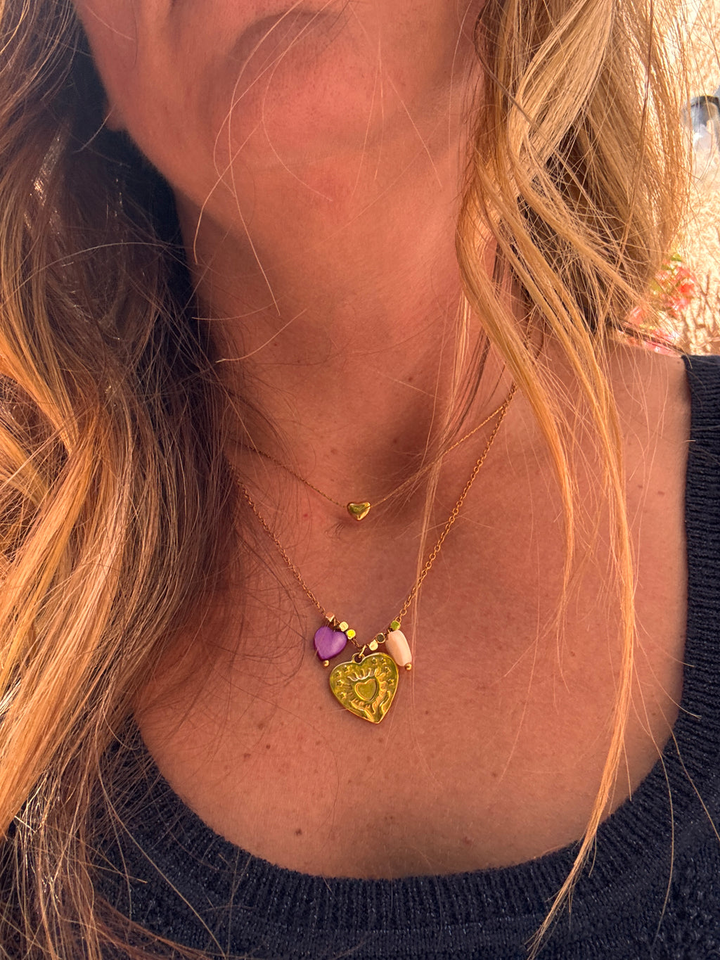 Collier Amour en acier inoxydable doré posé à plat, avec charm cœur et perles cœur en coquillage violet et blanc