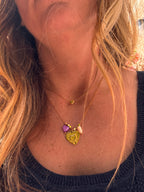Collier Amour en acier inoxydable doré posé à plat, avec charm cœur et perles cœur en coquillage violet et blanc