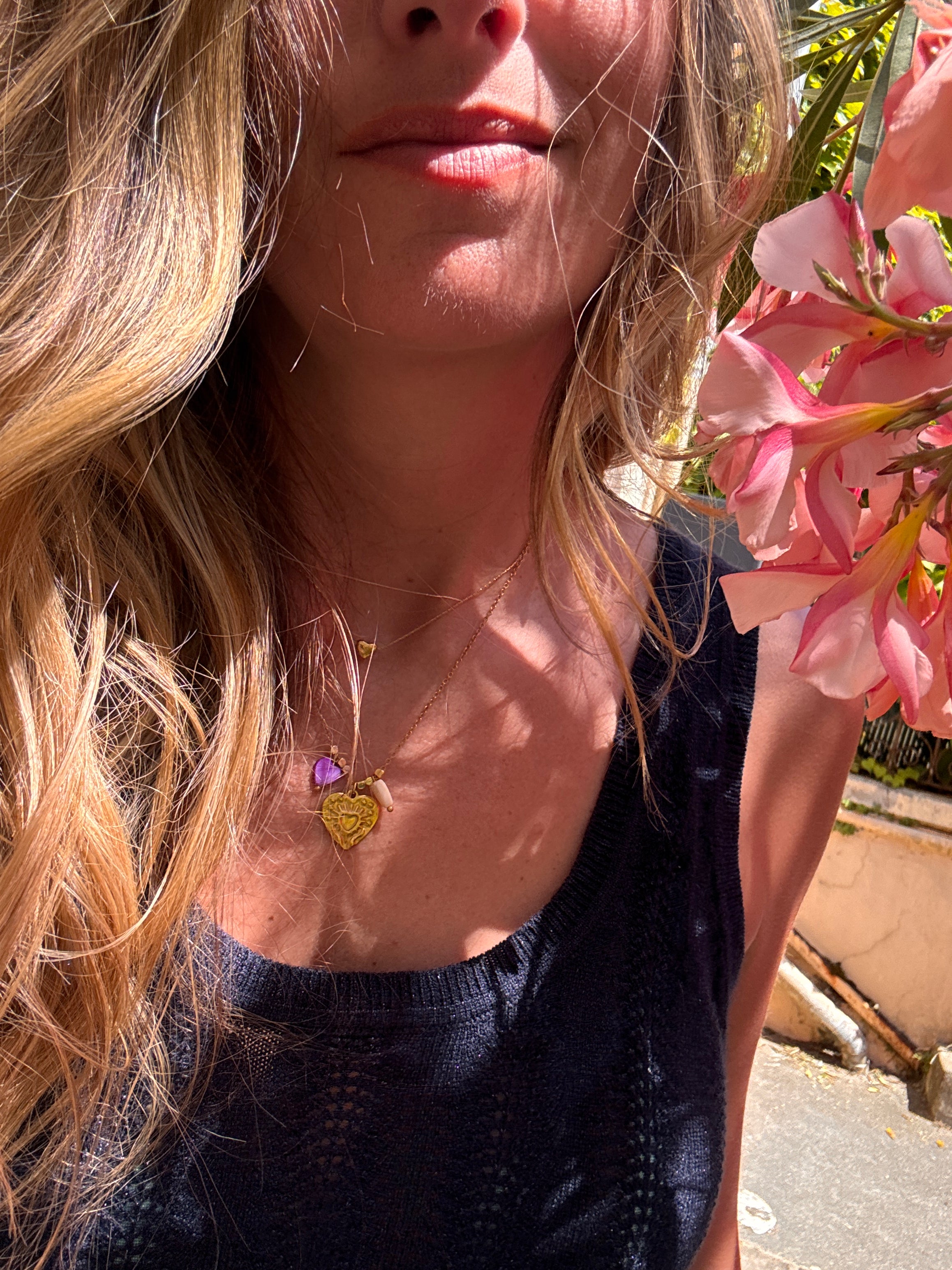 Collier Amour en acier inoxydable doré posé à plat, avec charm cœur et perles cœur en coquillage violet et blanc