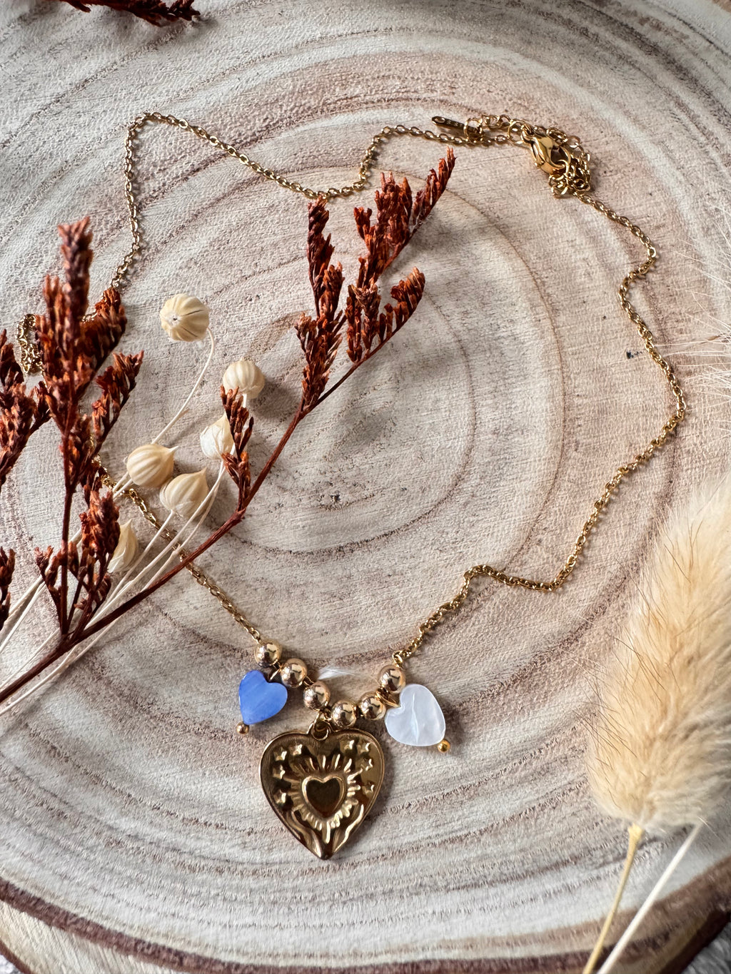 Collier Amour waterproof porté en bord de plage, chaîne dorée et cœurs en coquillage bleu
