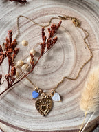 Collier Amour waterproof porté en bord de plage, chaîne dorée et cœurs en coquillage bleu