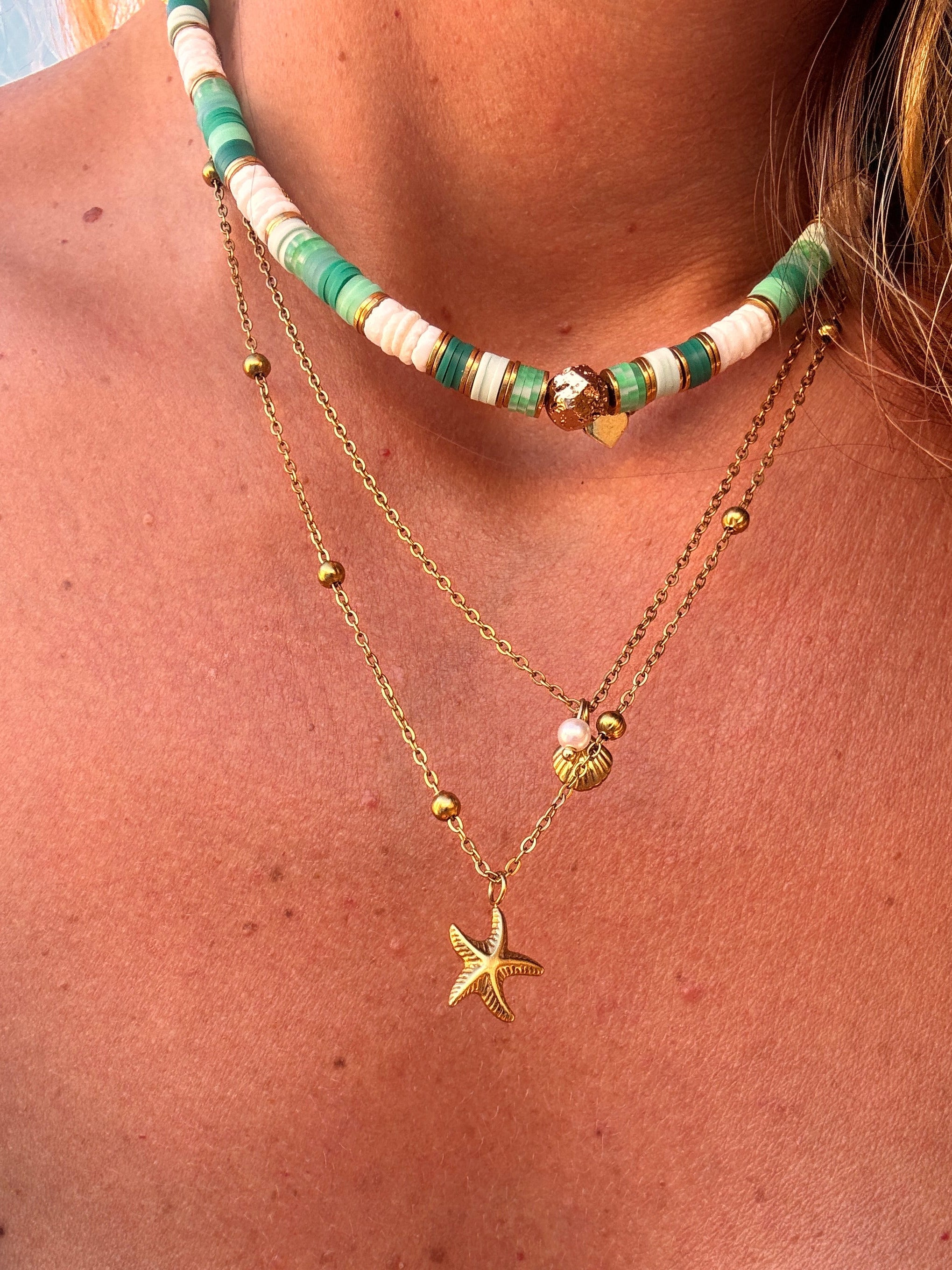 Collier Palma en perles heishi vertes et rose poudré porté près du cou, avec chaînes dorées en layering