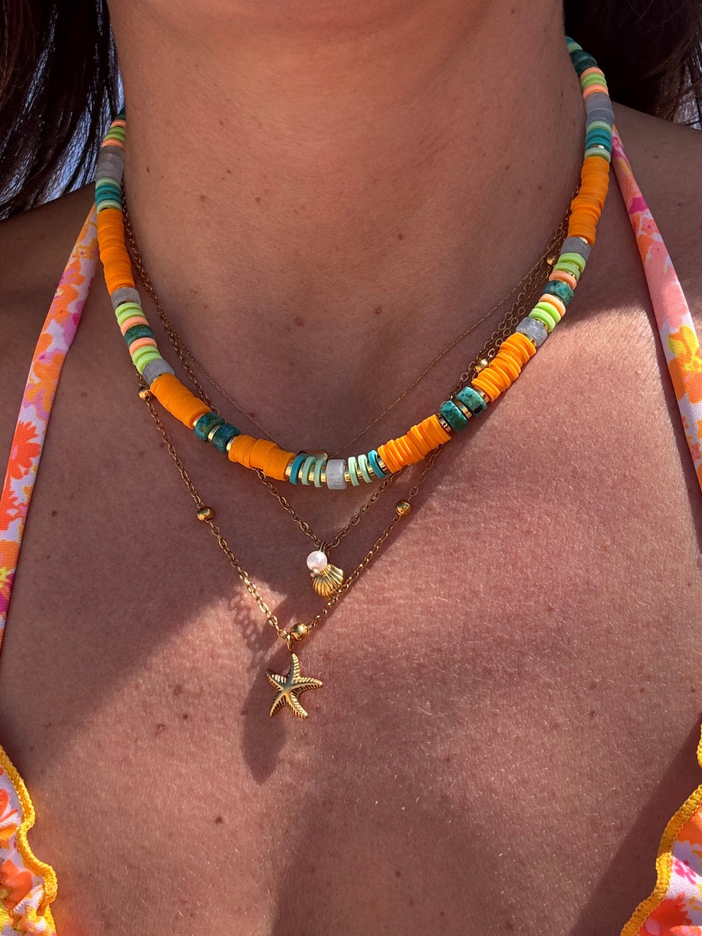 Collier tropical orange et vert porté à la plage