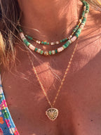 Détail du collier Palma : perle dorée martelée et pampille cœur entre perles heishi vertes
